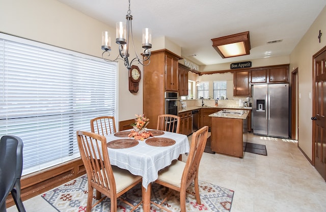 dining area with a textured ceiling, a notable chandelier, light tile patterned flooring, and sink