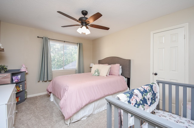 bedroom featuring ceiling fan, light colored carpet, and a textured ceiling