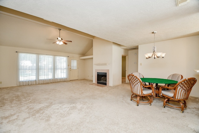 carpeted dining room featuring a textured ceiling, a tile fireplace, ceiling fan with notable chandelier, and vaulted ceiling