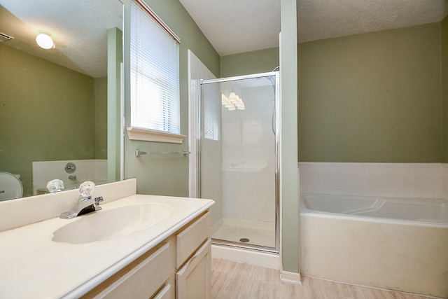 bathroom featuring separate shower and tub, vanity, wood-type flooring, and a textured ceiling