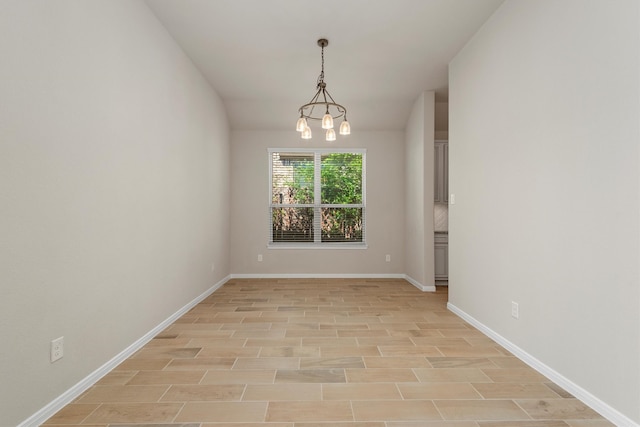 spare room featuring a notable chandelier and light wood-type flooring