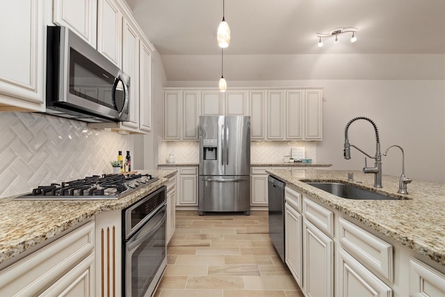 kitchen with white cabinets, sink, hanging light fixtures, light stone countertops, and appliances with stainless steel finishes