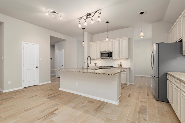 kitchen with a center island with sink, sink, light hardwood / wood-style floors, light stone counters, and stainless steel appliances