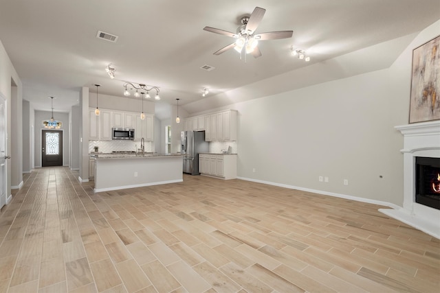 unfurnished living room with ceiling fan, sink, and light hardwood / wood-style floors