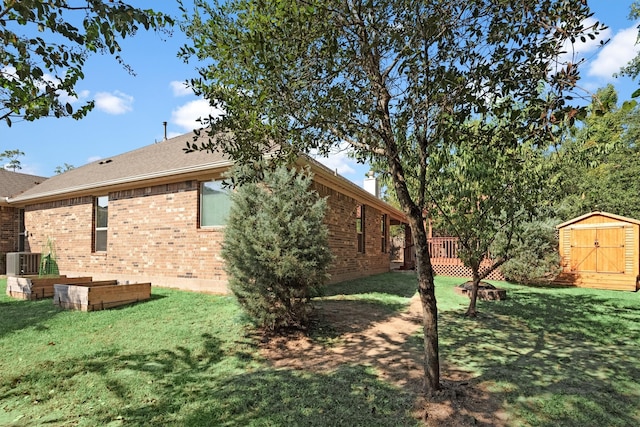 exterior space featuring a yard, central AC, and a storage unit