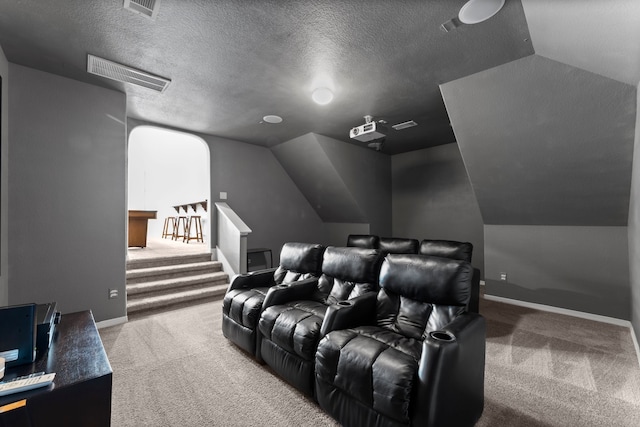 carpeted home theater with a textured ceiling and vaulted ceiling