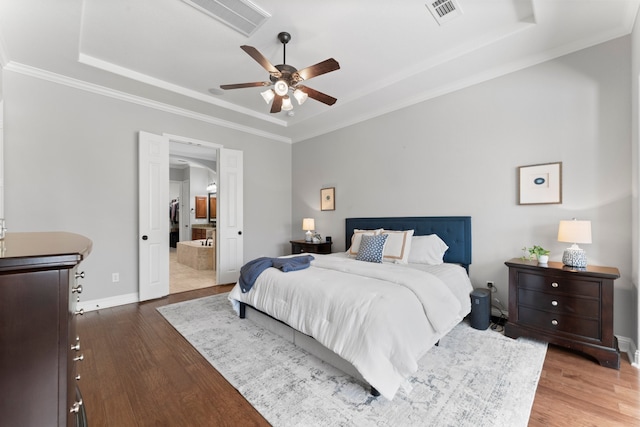 bedroom with a raised ceiling, ceiling fan, ensuite bathroom, and dark hardwood / wood-style floors