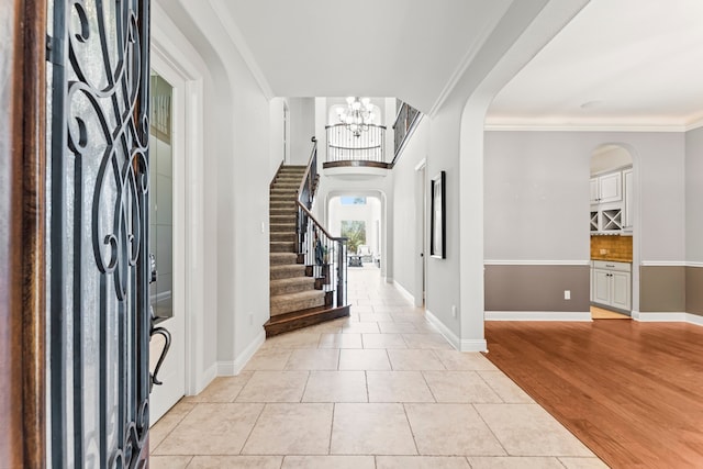 tiled entryway featuring a chandelier and crown molding