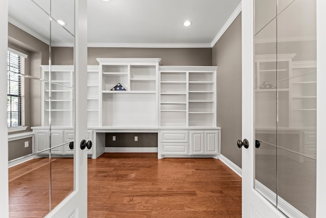 spacious closet featuring french doors, built in desk, and wood-type flooring