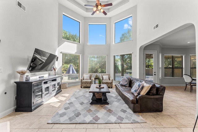 living room featuring ceiling fan, plenty of natural light, a towering ceiling, and light tile patterned floors