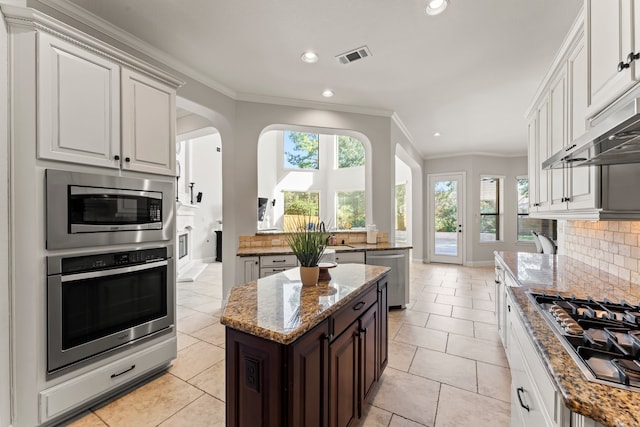 kitchen featuring white cabinets, a center island, light stone countertops, and appliances with stainless steel finishes