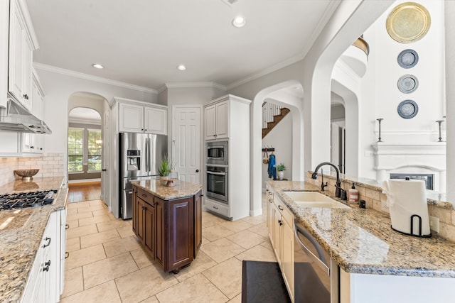 kitchen featuring appliances with stainless steel finishes, sink, light tile patterned floors, white cabinets, and a center island