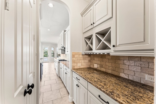 kitchen with backsplash, white cabinets, dark stone counters, and light tile patterned floors