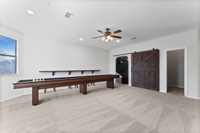 game room featuring a barn door, ceiling fan, and light carpet