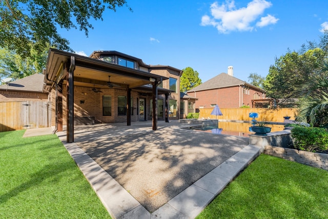 back of house with a fenced in pool, ceiling fan, a yard, and a patio