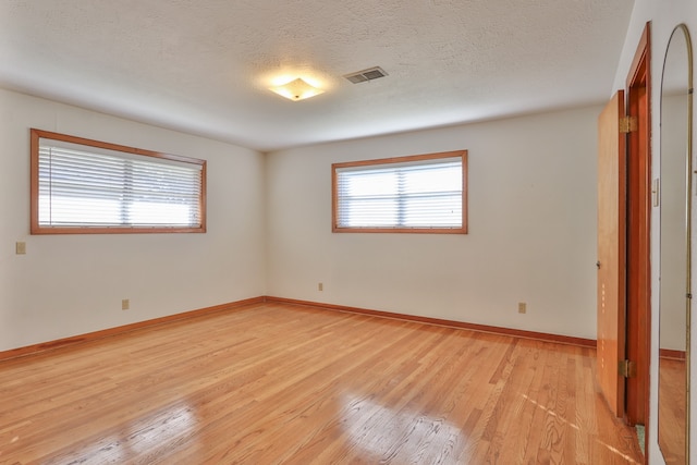 spare room featuring light hardwood / wood-style flooring and a textured ceiling