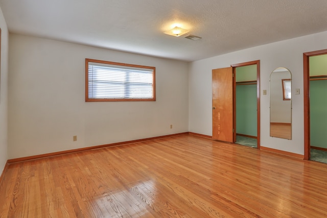 unfurnished room featuring a textured ceiling and light hardwood / wood-style flooring