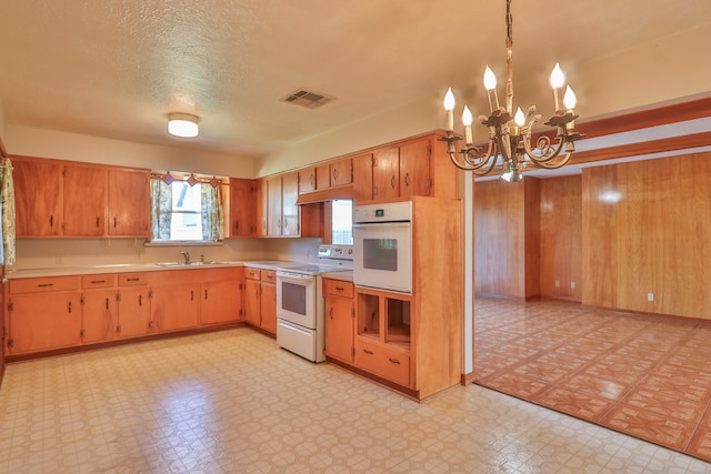 kitchen with sink, an inviting chandelier, pendant lighting, a textured ceiling, and white appliances