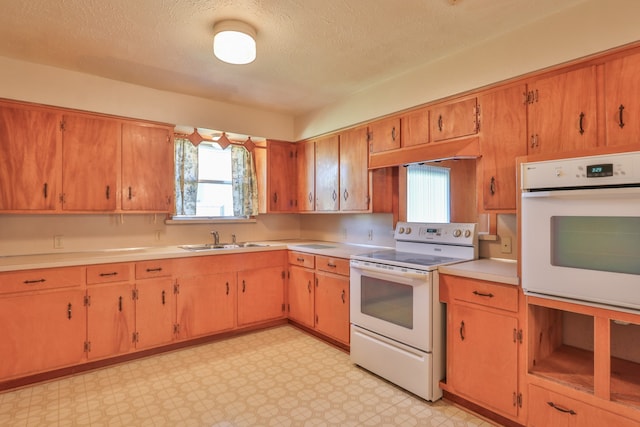 kitchen with a textured ceiling, sink, and white appliances