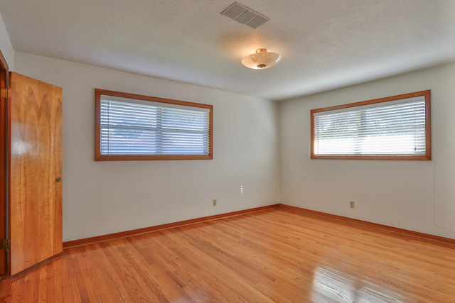 empty room with a textured ceiling and light wood-type flooring