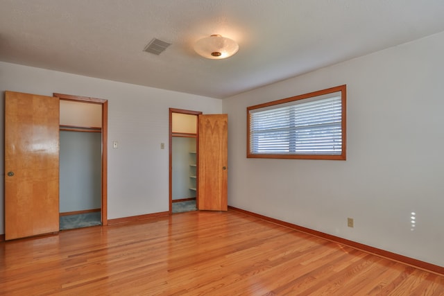 unfurnished bedroom with a textured ceiling and light hardwood / wood-style flooring