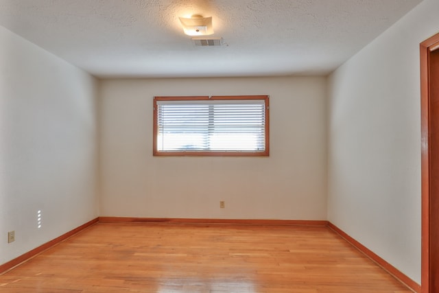 spare room featuring light hardwood / wood-style floors and a textured ceiling