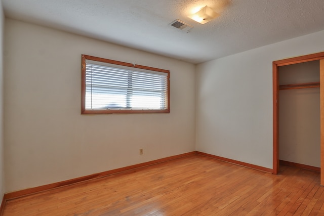 unfurnished bedroom with a closet, a textured ceiling, and light hardwood / wood-style flooring