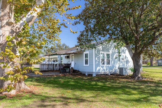 rear view of house with central AC unit and a yard