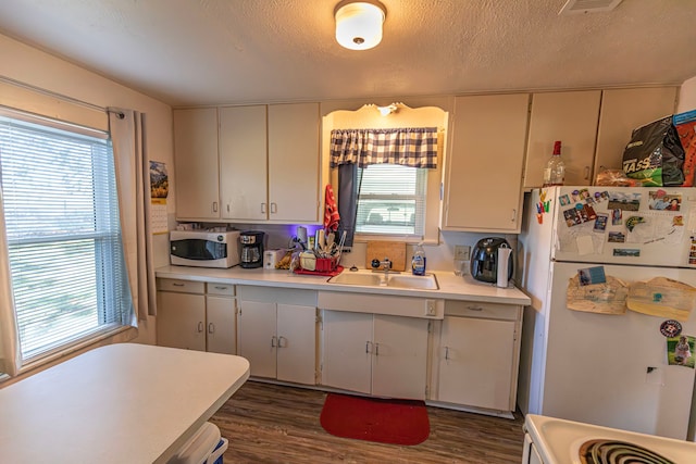 kitchen featuring white appliances, dark hardwood / wood-style floors, a textured ceiling, and sink