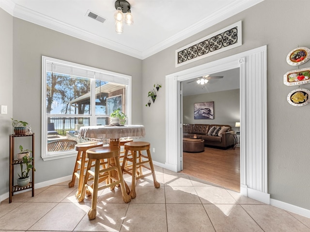 tiled dining space featuring ceiling fan and crown molding