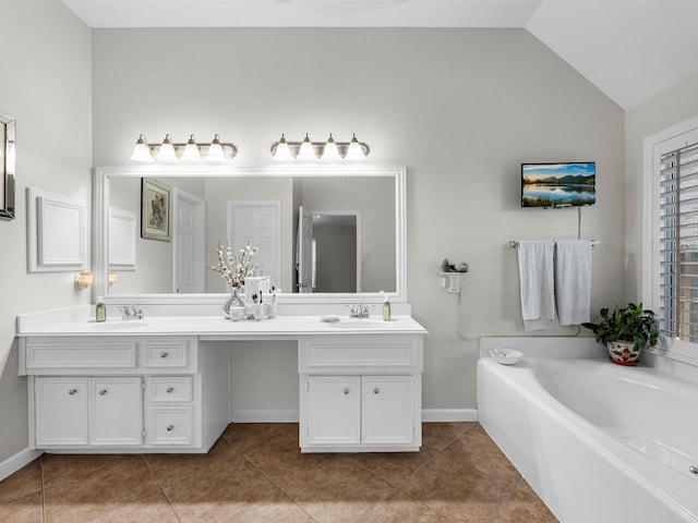 bathroom with a bathing tub, vanity, tile patterned flooring, and vaulted ceiling