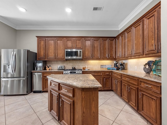 kitchen with a center island, decorative backsplash, light stone countertops, ornamental molding, and appliances with stainless steel finishes