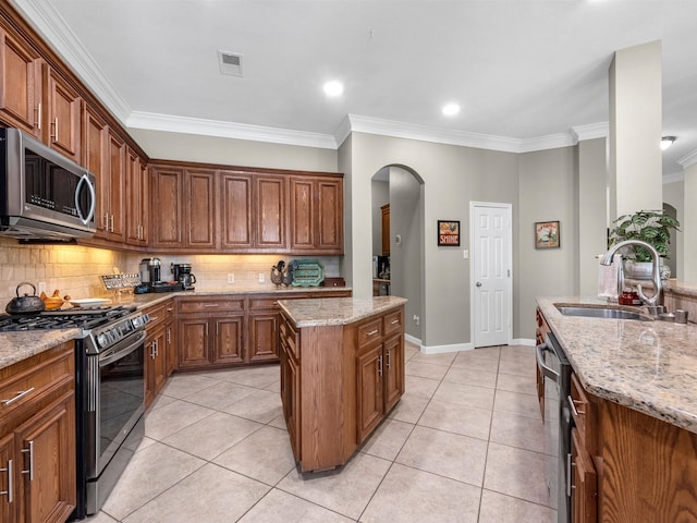 kitchen featuring sink, crown molding, tasteful backsplash, light stone counters, and stainless steel appliances