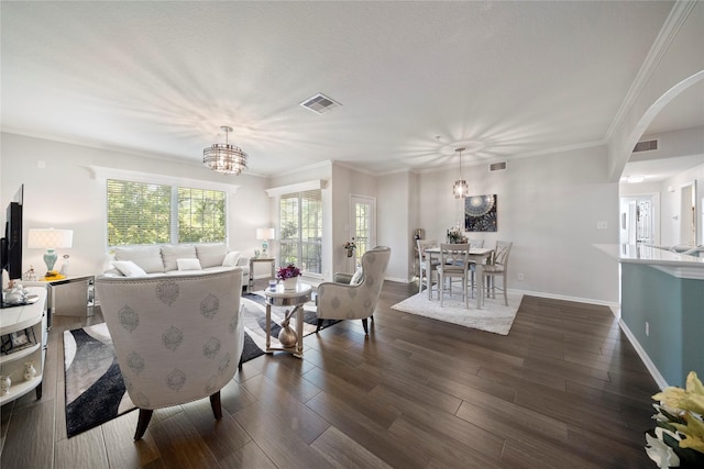 living room featuring dark wood-type flooring, a chandelier, and ornamental molding