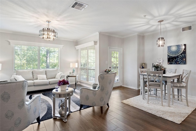 living room featuring dark wood-type flooring, a chandelier, and ornamental molding