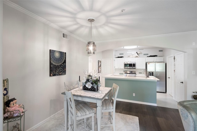 dining space featuring hardwood / wood-style floors, crown molding, and an inviting chandelier