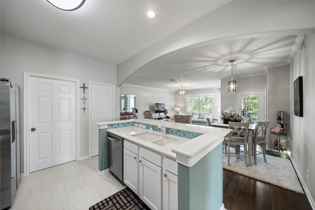 kitchen with pendant lighting, a center island with sink, sink, appliances with stainless steel finishes, and white cabinetry