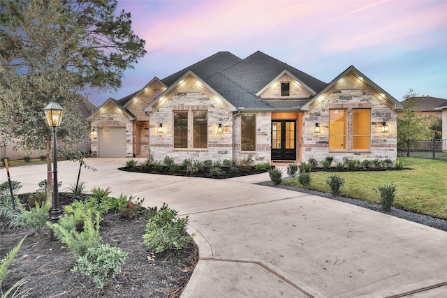 view of front of house with french doors, a garage, and a lawn