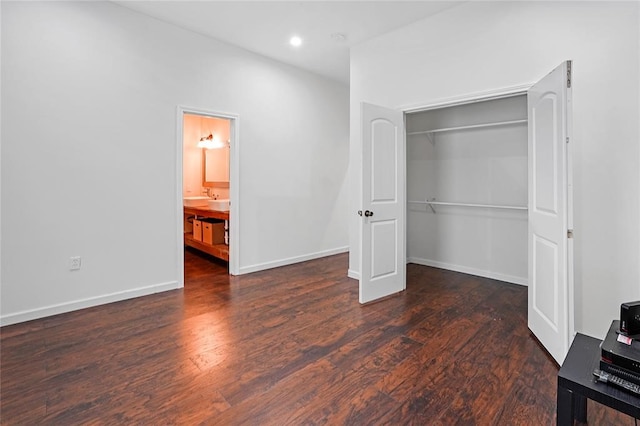 unfurnished bedroom featuring dark hardwood / wood-style floors, ensuite bath, and a closet