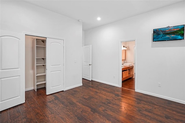 unfurnished bedroom featuring dark hardwood / wood-style flooring, ensuite bathroom, and a spacious closet