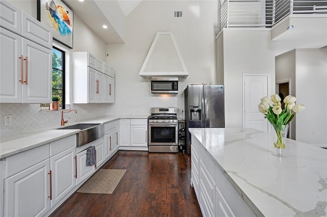 kitchen with white cabinetry, light stone counters, high vaulted ceiling, and stainless steel appliances