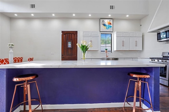 kitchen featuring a breakfast bar area, dark hardwood / wood-style floors, a large island, white cabinetry, and stainless steel appliances