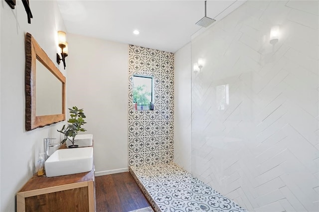 bathroom with hardwood / wood-style floors, vanity, and a tile shower