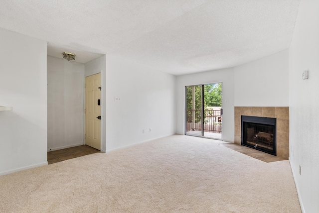 unfurnished living room featuring a tile fireplace, light carpet, and a textured ceiling