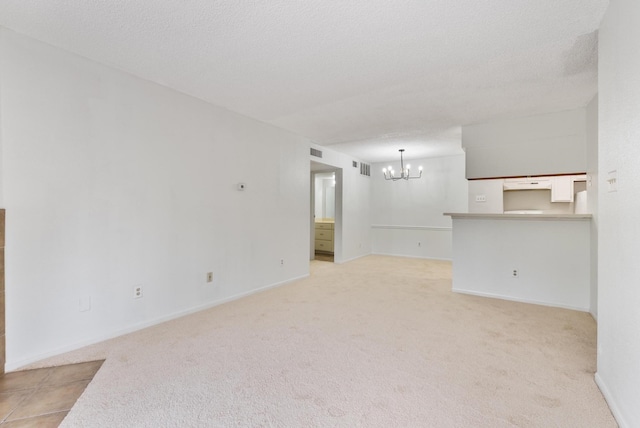 carpeted spare room with a chandelier and a textured ceiling