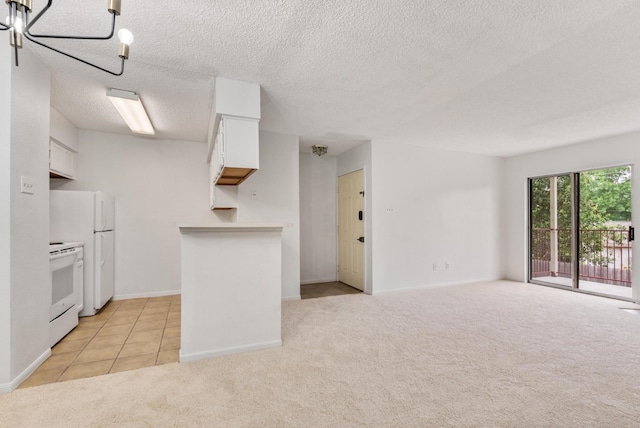 kitchen featuring a notable chandelier, a textured ceiling, white appliances, light carpet, and white cabinets