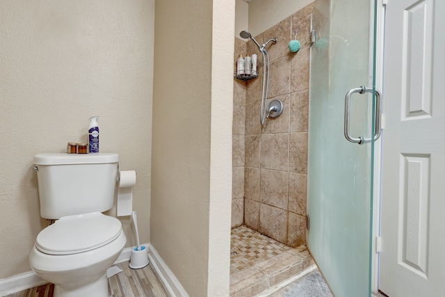 bathroom featuring hardwood / wood-style floors, an enclosed shower, and toilet