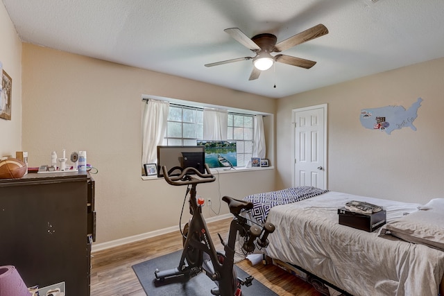 bedroom featuring ceiling fan, light wood-type flooring, and a textured ceiling