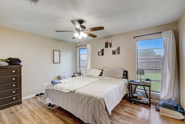 bedroom with ceiling fan, light hardwood / wood-style flooring, and multiple windows