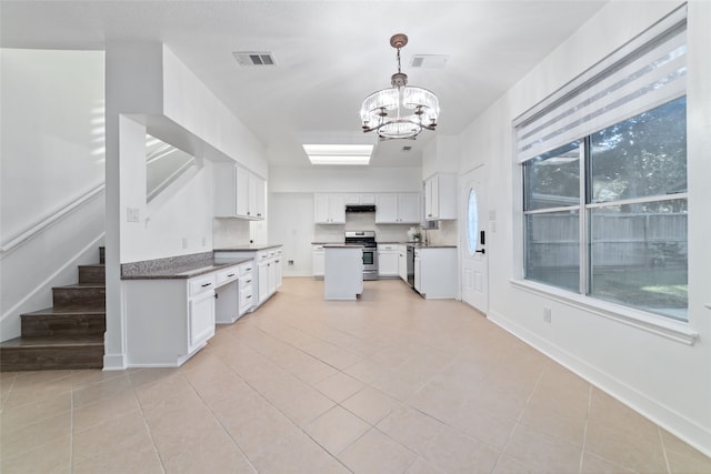 kitchen featuring appliances with stainless steel finishes, light tile patterned floors, decorative light fixtures, an inviting chandelier, and white cabinets